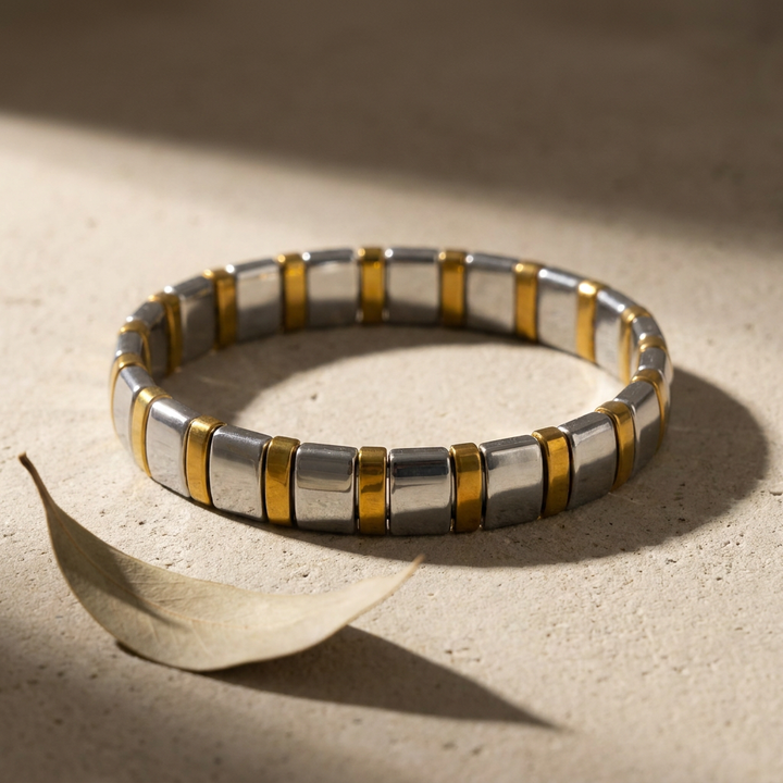 Delemon featuring a uniform two-tone stretch bracelet alternating polished silver-grey hematite blocks with slim gold metallic spacer beads