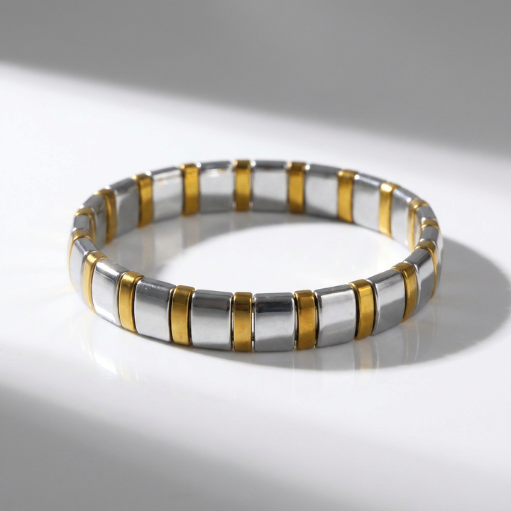 Delemon featuring a uniform two-tone stretch bracelet alternating polished silver-grey hematite blocks with slim gold metallic spacer beads