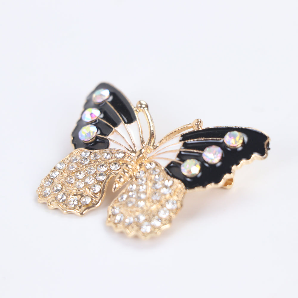 Black and white enamel butterfly brooch pin with iridescent AB crystals and clear pavé lower wings on a white background by Delemon