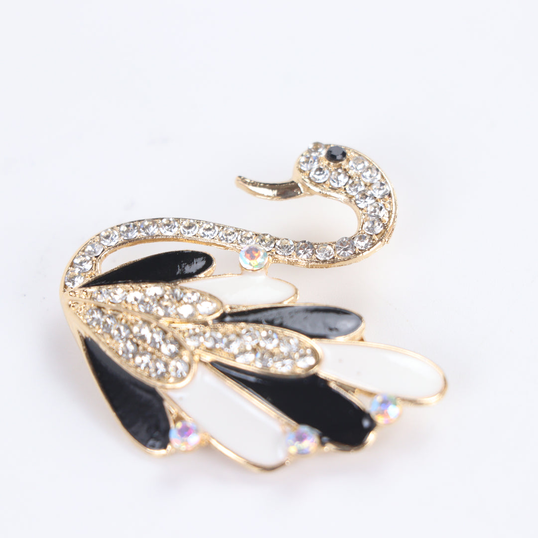 Gold-tone swan brooch pin with black and white enamel feathers, clear crystals, and iridescent rhinestone accents on a white background by Delemon