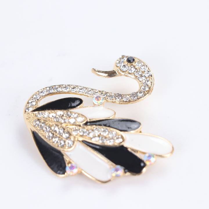 Gold-tone swan brooch pin with black and white enamel feathers, clear crystals, and iridescent rhinestone accents on a white background by Delemon