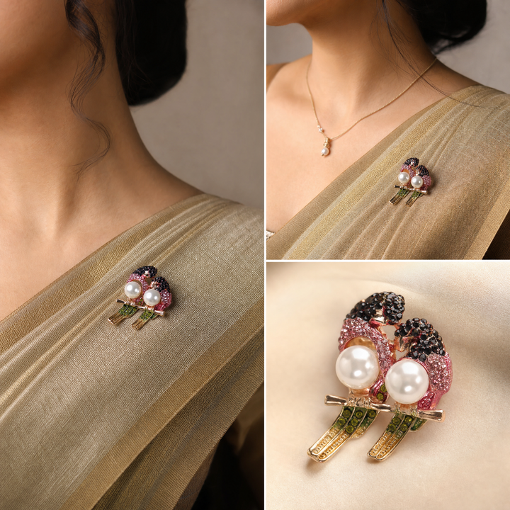 Gold-tone perched lovebirds brooch pin with pink and dark red crystals, olive green tail feathers, and pearl bodies 
