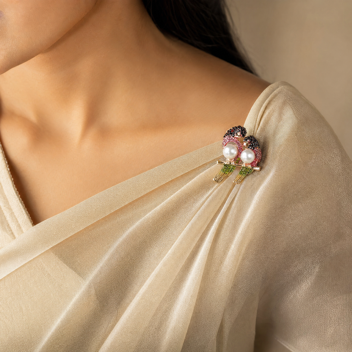 Gold-tone perched lovebirds brooch pin with pink and dark red crystals, olive green tail feathers, and pearl bodies 