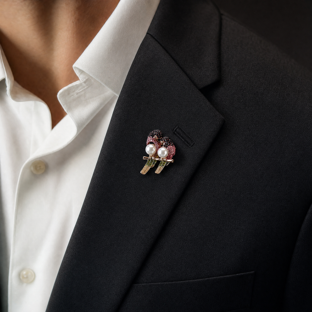 Gold-tone perched lovebirds brooch pin with pink and dark red crystals, olive green tail feathers, and pearl bodies 