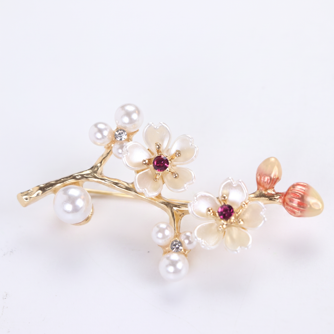 Gold-tone cherry blossom branch brooch pin with pearlescent white enamel flowers, ruby pink crystals, and pearl