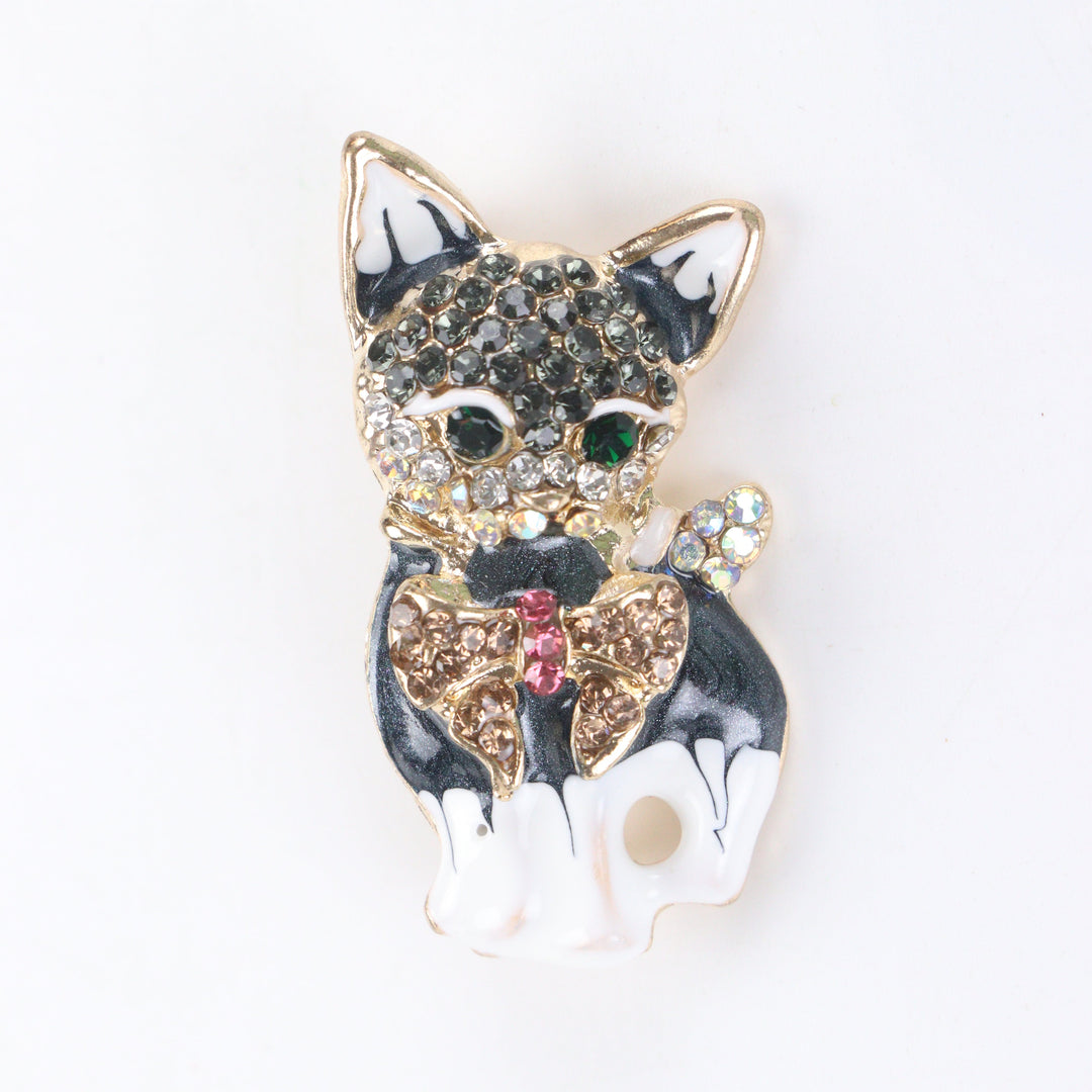 Gold-tone sitting French Bulldog brooch pin with black and white enamel finish, crystal bow tie, and rhinestone face details on a white background by Delemon