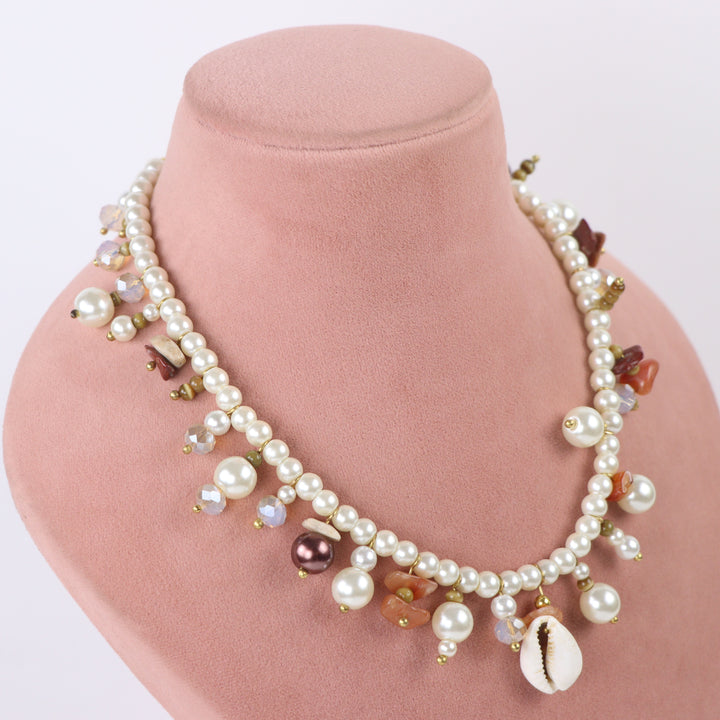 De-lemon cowrie shell center charm pearl necklace with dangling beads and matching cluster earrings on display mannequin.