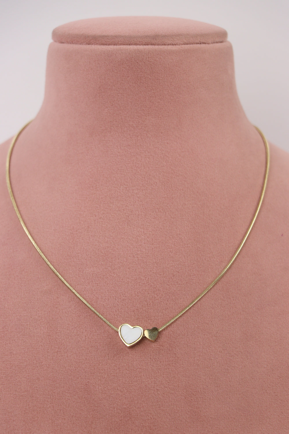 Delemon high-quality gold plated snake chain necklace with double heart charms displayed elegantly on a pink bust.