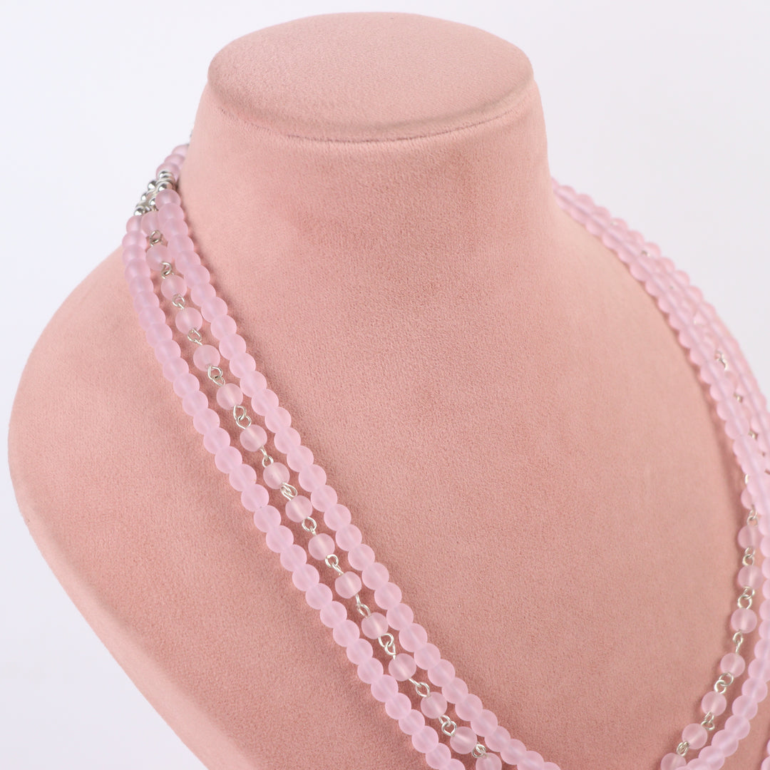 Frosted matte pink multi-strand glass bead necklace and matching drop earrings on a display mannequin - Delemon Collection.
