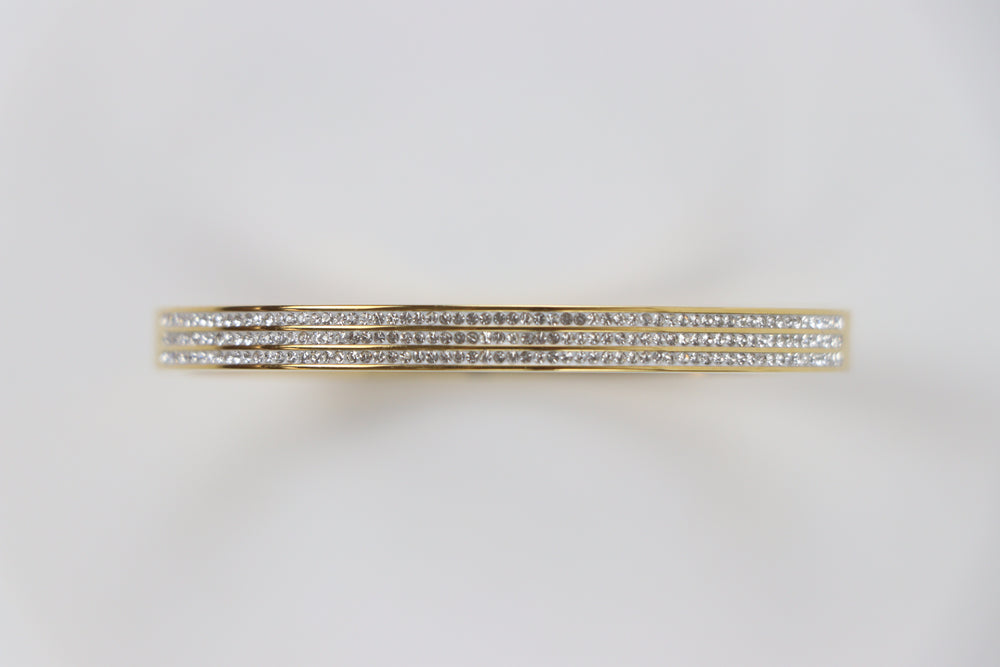 Delemon gold rigid bangle bracelet featuring three rows of clear pavé crystals in waterproof 18k gold plated stainless steel