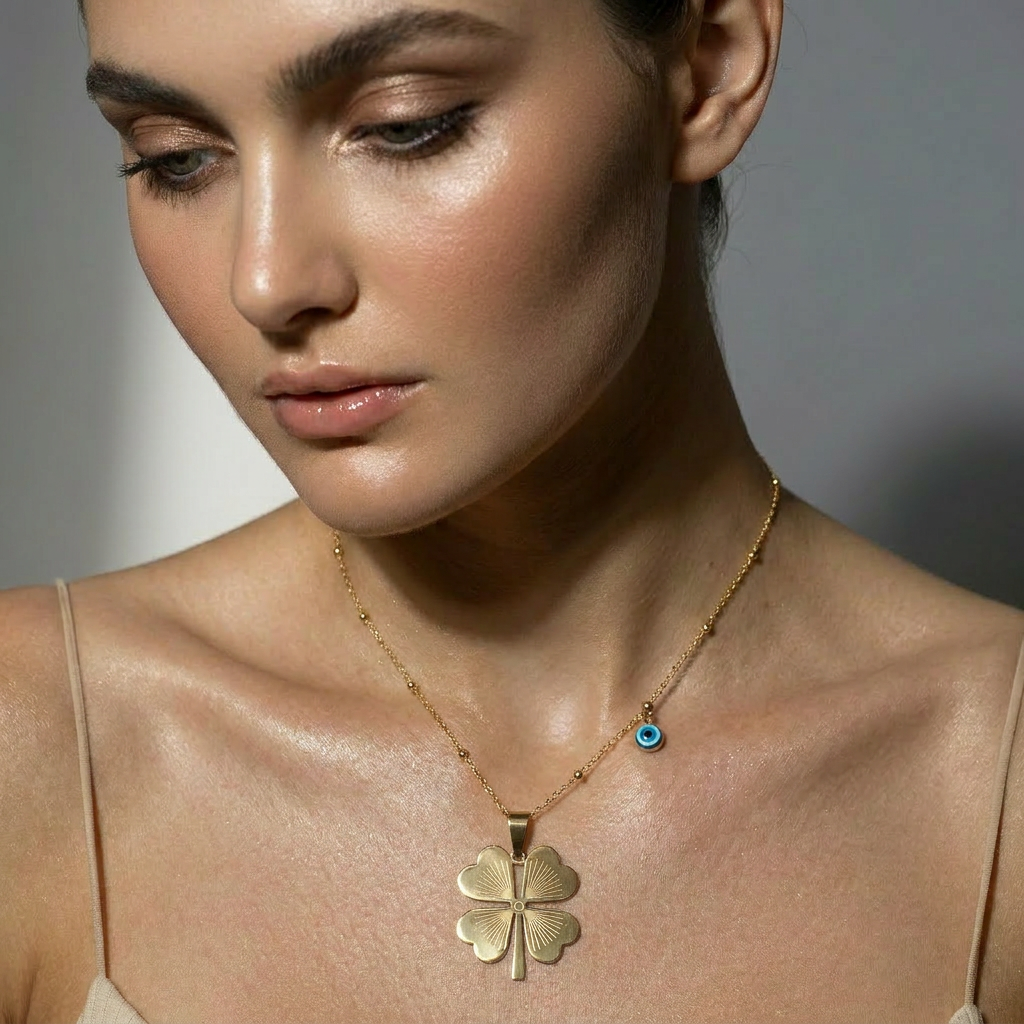 Delemon high-quality gold plated delicate bead chain necklace featuring a large central four-leaf clover pendant with an engraved pattern and a small hanging blue evil eye charm
