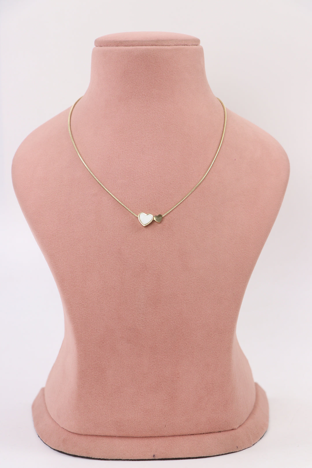 Delemon high-quality gold plated snake chain necklace with a white enamel heart pendant and mini heart charm, styled on a pink mannequin bust.