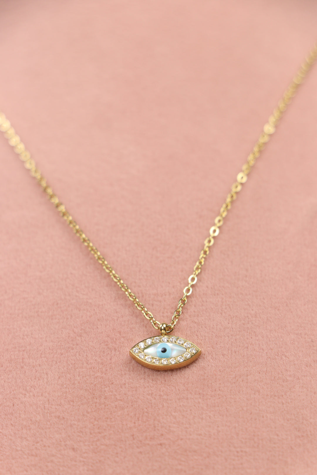 Delemon high-quality gold plated chain necklace featuring a small evil eye pendant with a mother-of-pearl center and crystal border close-up view.