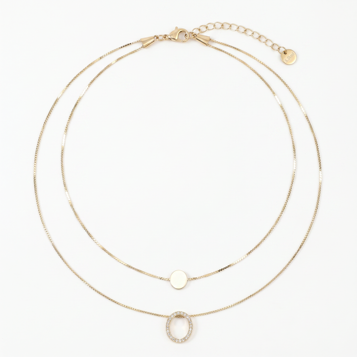 Delemon high-quality gold plated double-layer necklace featuring a top delicate chain with a smooth round disc and a bottom chain with a crystal pave oval ring pendant