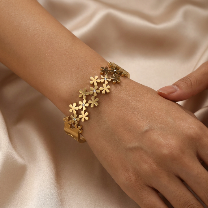 Delemon high-quality gold plated stainless steel bangle bracelet featuring an intricate clustered design of small five-petal flowers accented with delicate crystals