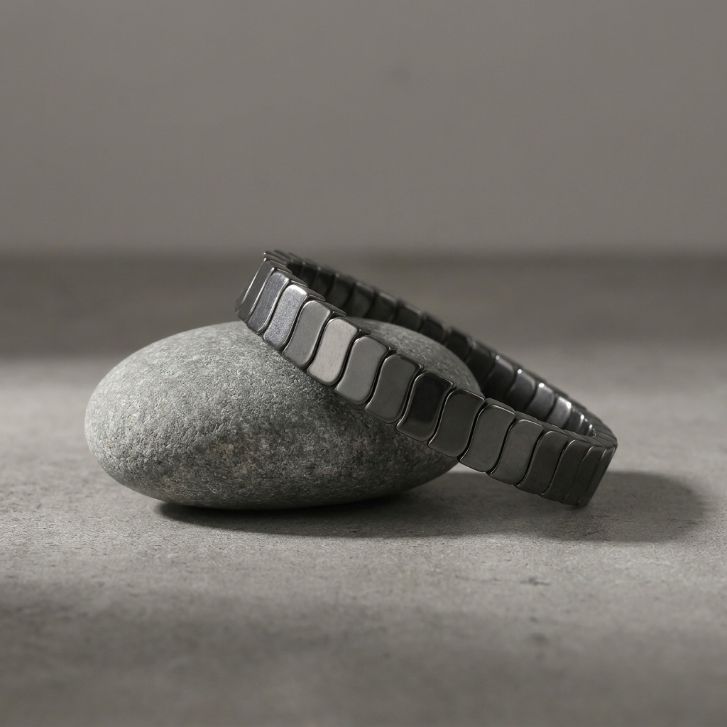 Delemon featuring a uniform stretch bracelet with slim, gently curved polished metallic hematite rectangular drum blocks