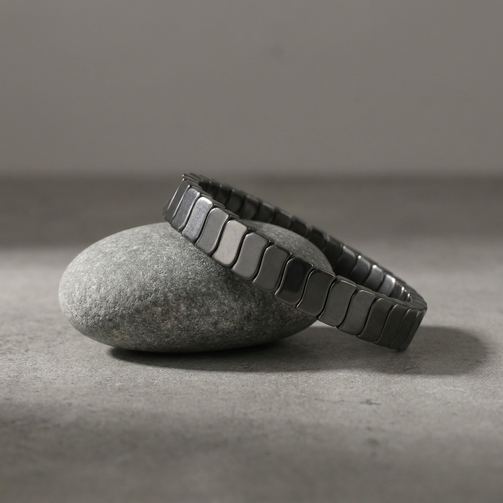 Delemon featuring a uniform stretch bracelet with slim, gently curved polished metallic hematite rectangular drum blocks