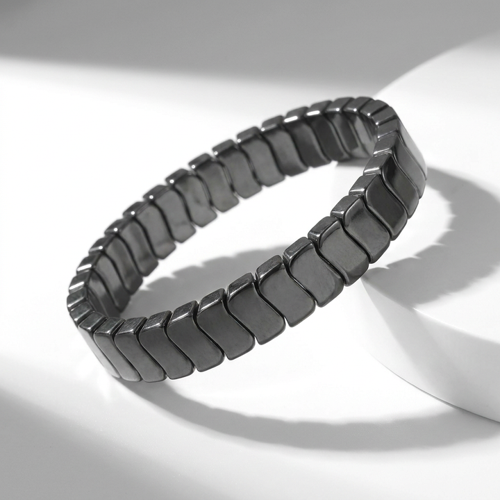 Delemon featuring a uniform stretch bracelet with slim, gently curved polished metallic hematite rectangular drum blocks