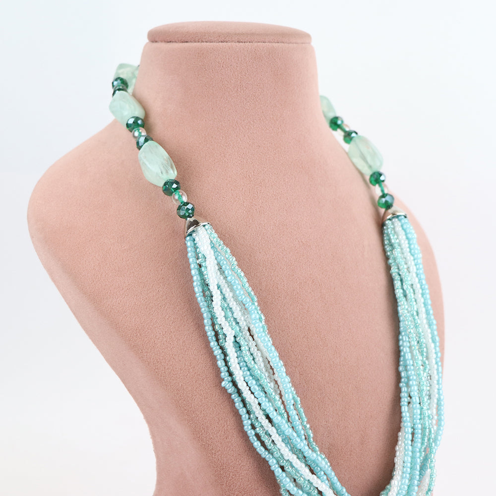 Side view of Delemon high-quality multi-strand necklace, highlighting the detailed transition from light blue seed beads to larger green crystal accents near the collar