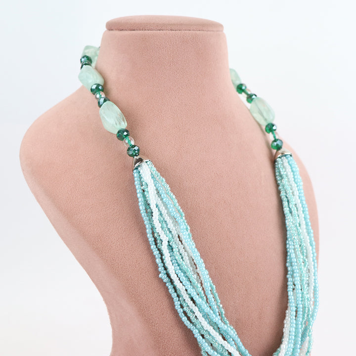 Side view of Delemon high-quality multi-strand necklace, highlighting the detailed transition from light blue seed beads to larger green crystal accents near the collar
