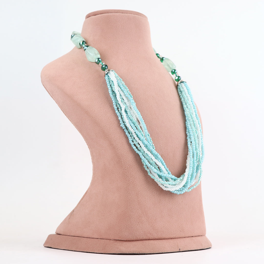 Three-quarter profile view of Delemon high-quality multi-strand necklace, showcasing how the light blue and white seed bead layers drape on a pink display bust.