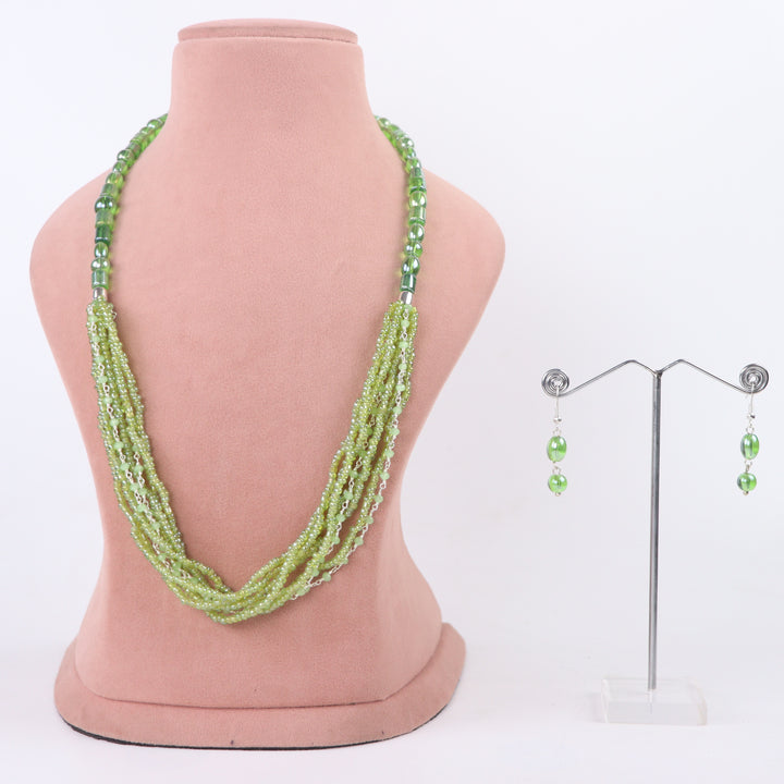 Olive green multi-strand seed bead necklace with chain accents and matching earrings on a pink display - delemon Collection.
