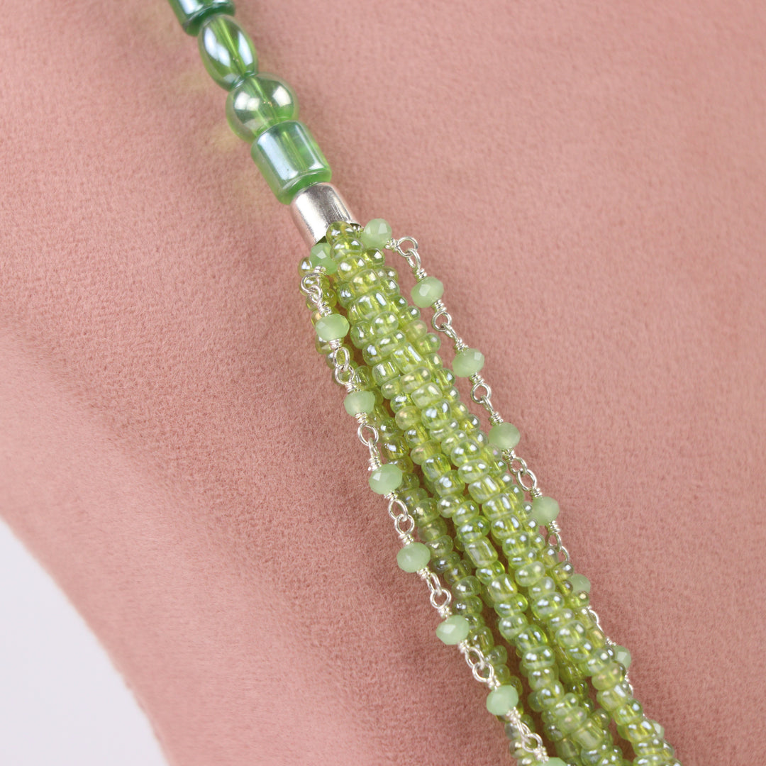 Olive green multi-strand seed bead necklace with chain accents and matching earrings on a pink display - delemon Collection.