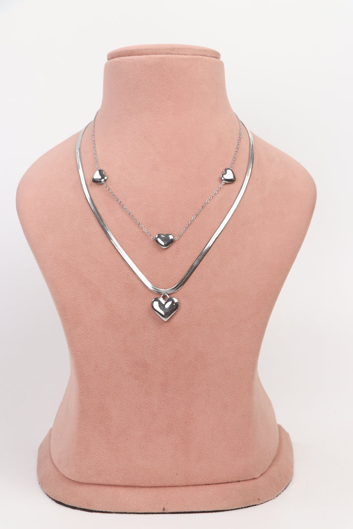Delemon high-quality silver polished layered necklace featuring a delicate chain with small heart stations and a thick snake chain with a central statement heart pendant full front view.