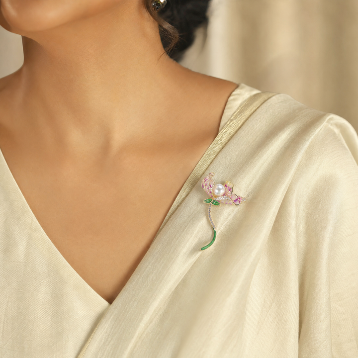 Gold-tone orchid brooch pin featuring purple gradient enamel petals, a large center pearl, and a curved green stem 