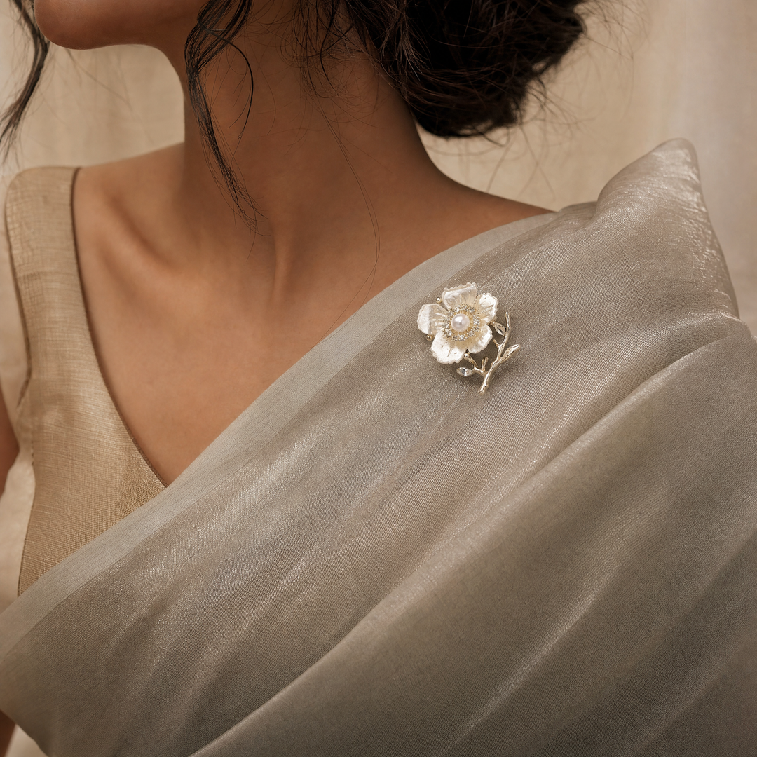 Gold-tone white enamel flower brooch pin with center pearl, rhinestone halo, and crystal branch accents