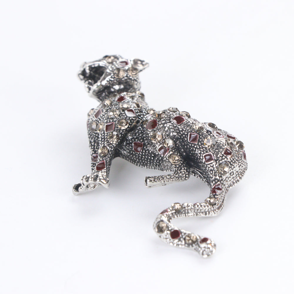 Antique silver-tone stalking leopard brooch pin encrusted with smoky crystals and red enamel leopard spots on a white background by Delemon