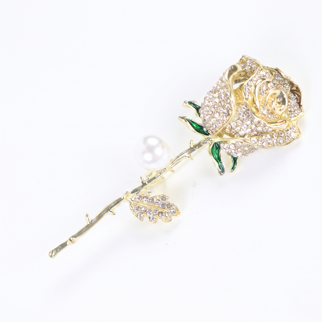 Gold rose brooch pin encrusted with pave crystals, green enamel accents, and a pearl 