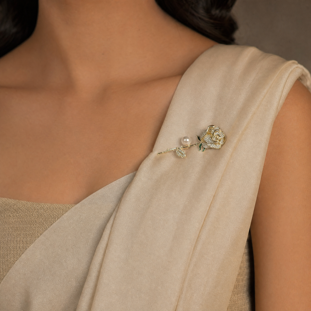 Gold rose brooch pin encrusted with pave crystals, green enamel accents, and a pearl 