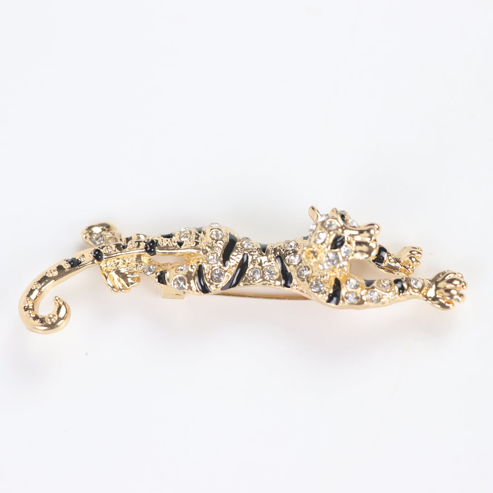 Gold prowling tiger brooch pin encrusted with clear pavé crystals and black enamel stripes on a white background by Delemon