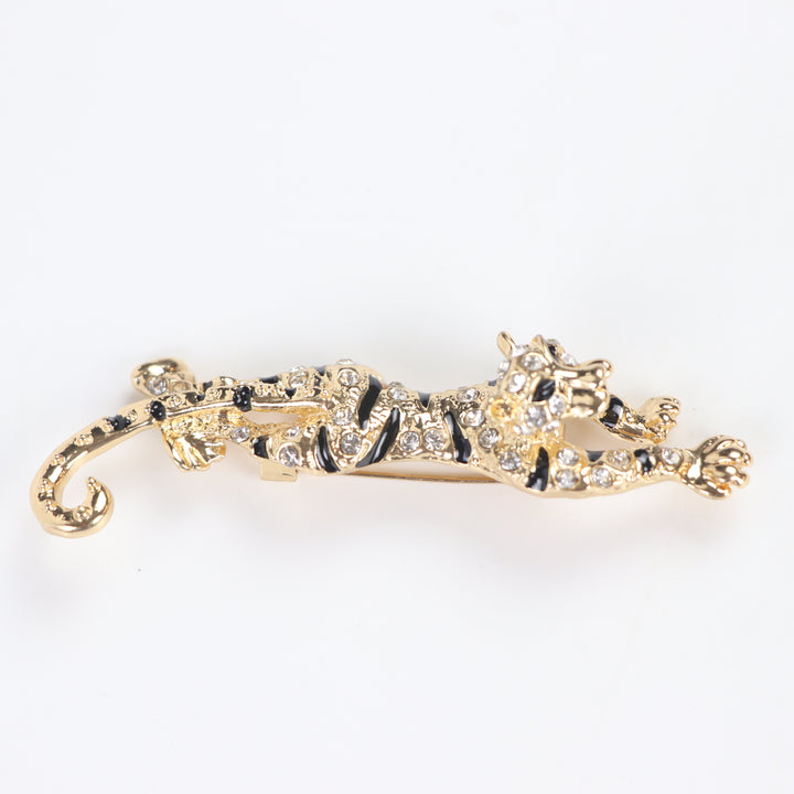Gold prowling tiger brooch pin encrusted with clear pavé crystals and black enamel stripes on a white background by Delemon