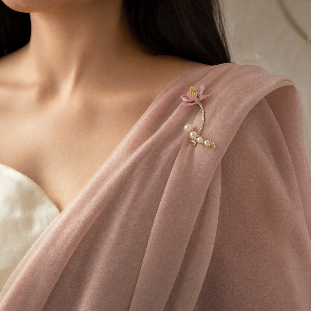 Gold-tone brooch pin featuring a pink enamel lily flower, pavé rhinestone stem, and a curved strand of white pearls 