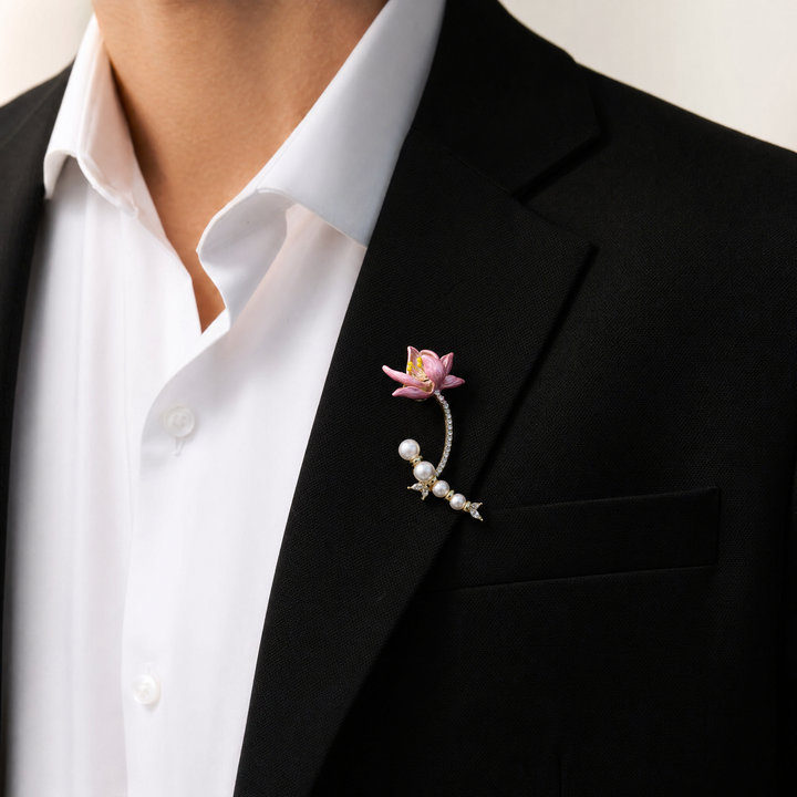 Gold-tone brooch pin featuring a pink enamel lily flower, pavé rhinestone stem, and a curved strand of white pearls 