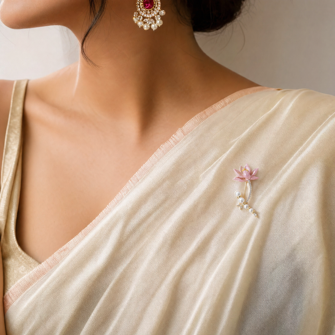 Gold-tone brooch pin featuring a pink enamel lily flower, pavé rhinestone stem, and a curved strand of white pearls 