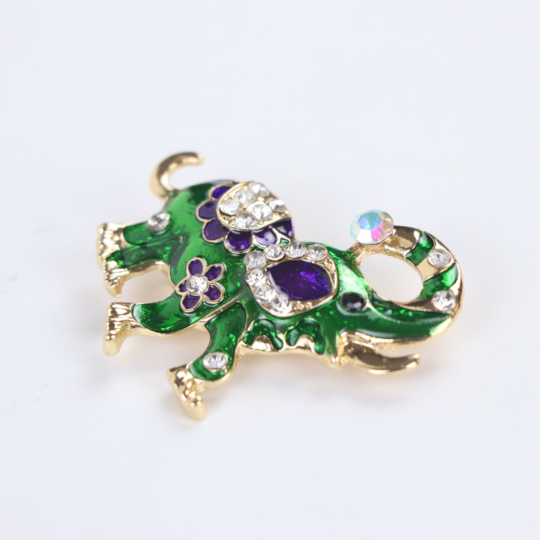 Vibrant green enamel elephant brooch pin with purple floral details and sparkling crystal accents on a white background by Delemon