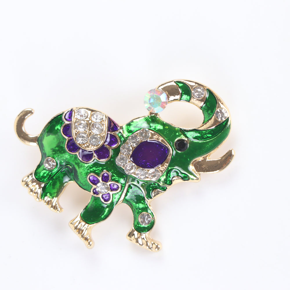 Vibrant green enamel elephant brooch pin with purple floral details and sparkling crystal accents on a white background by Delemon