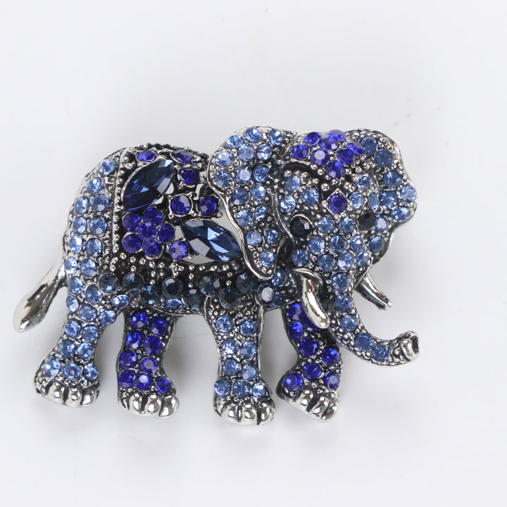 Antique silver-tone elephant brooch pin fully pavé-set with gradient blue crystals on a white background by Delemon