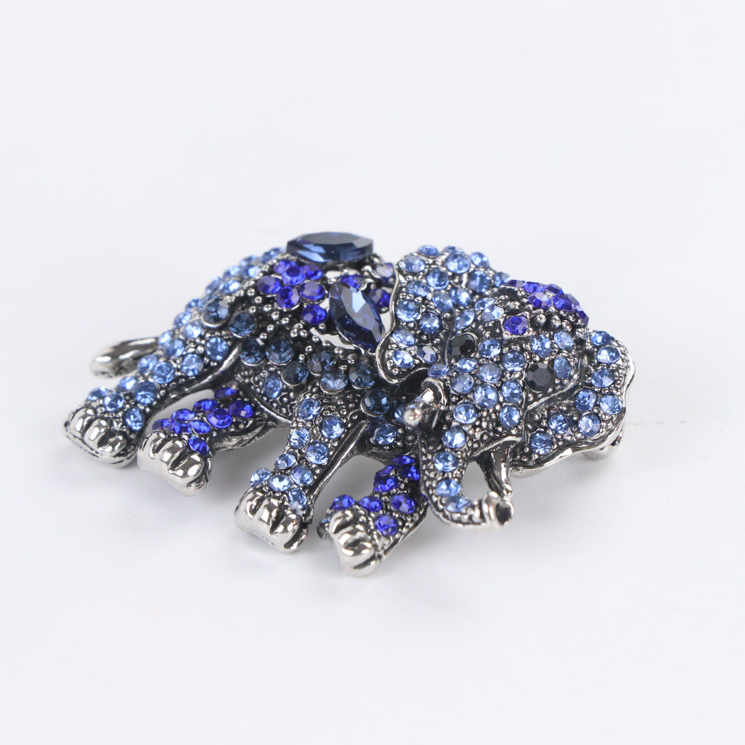 Antique silver-tone elephant brooch pin fully pavé-set with gradient blue crystals on a white background by Delemon