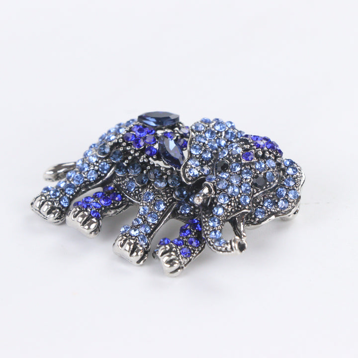 Antique silver-tone elephant brooch pin fully pavé-set with gradient blue crystals on a white background by Delemon