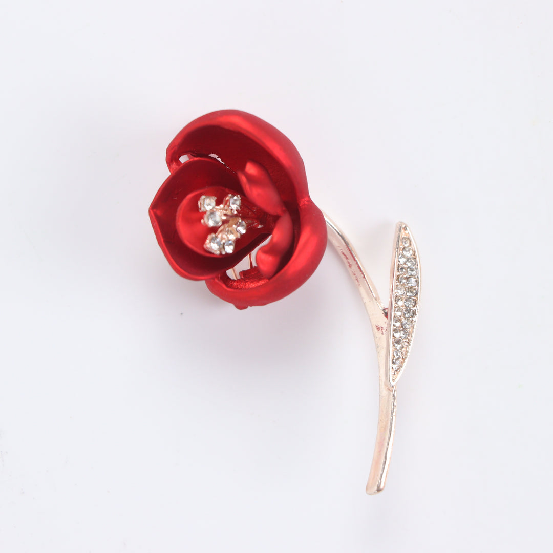 Matte red flower brooch pin with crystal stamen and crystal leaf on a rose gold stem against a white background by Delemon