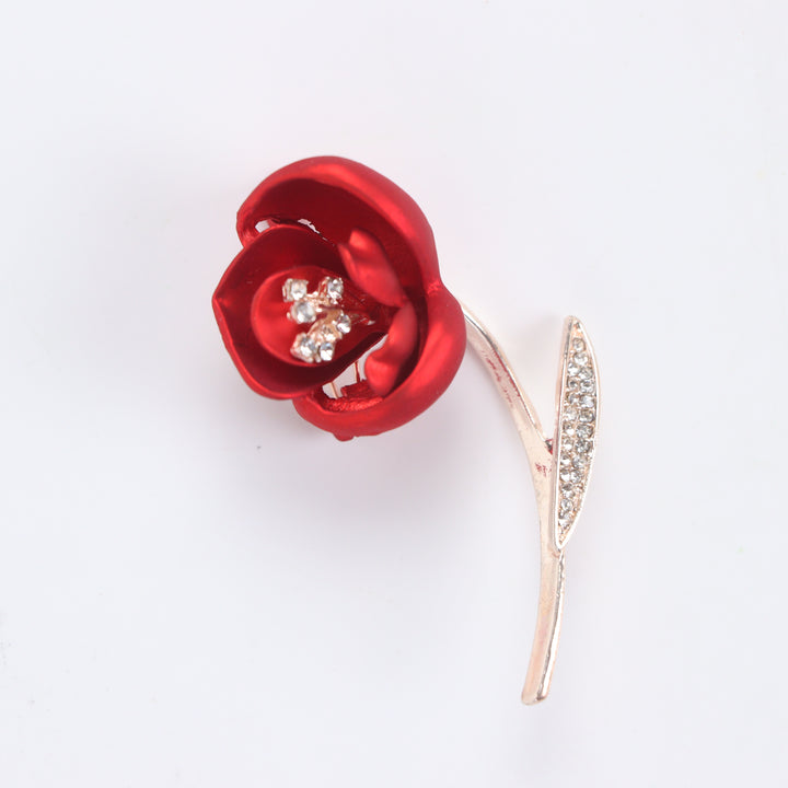 Matte red flower brooch pin with crystal stamen and crystal leaf on a rose gold stem against a white background by Delemon