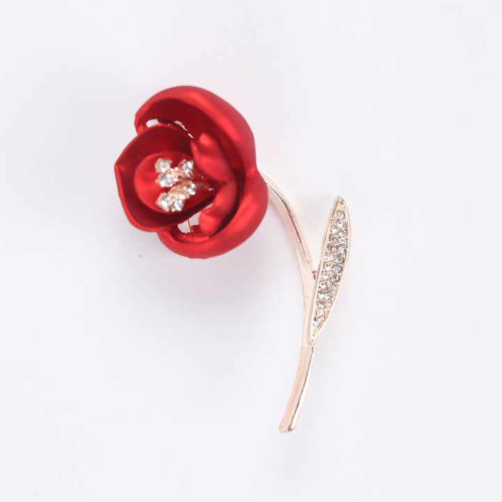 Matte red flower brooch pin with crystal stamen and crystal leaf on a rose gold stem against a white background by Delemon