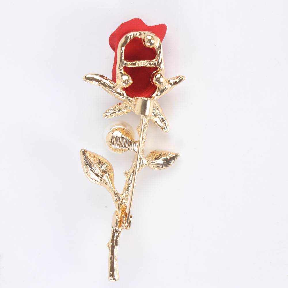 Matte red rose flower brooch pin with a pearl accent and pave crystal leaves on a gold stem against a white background by Delemon