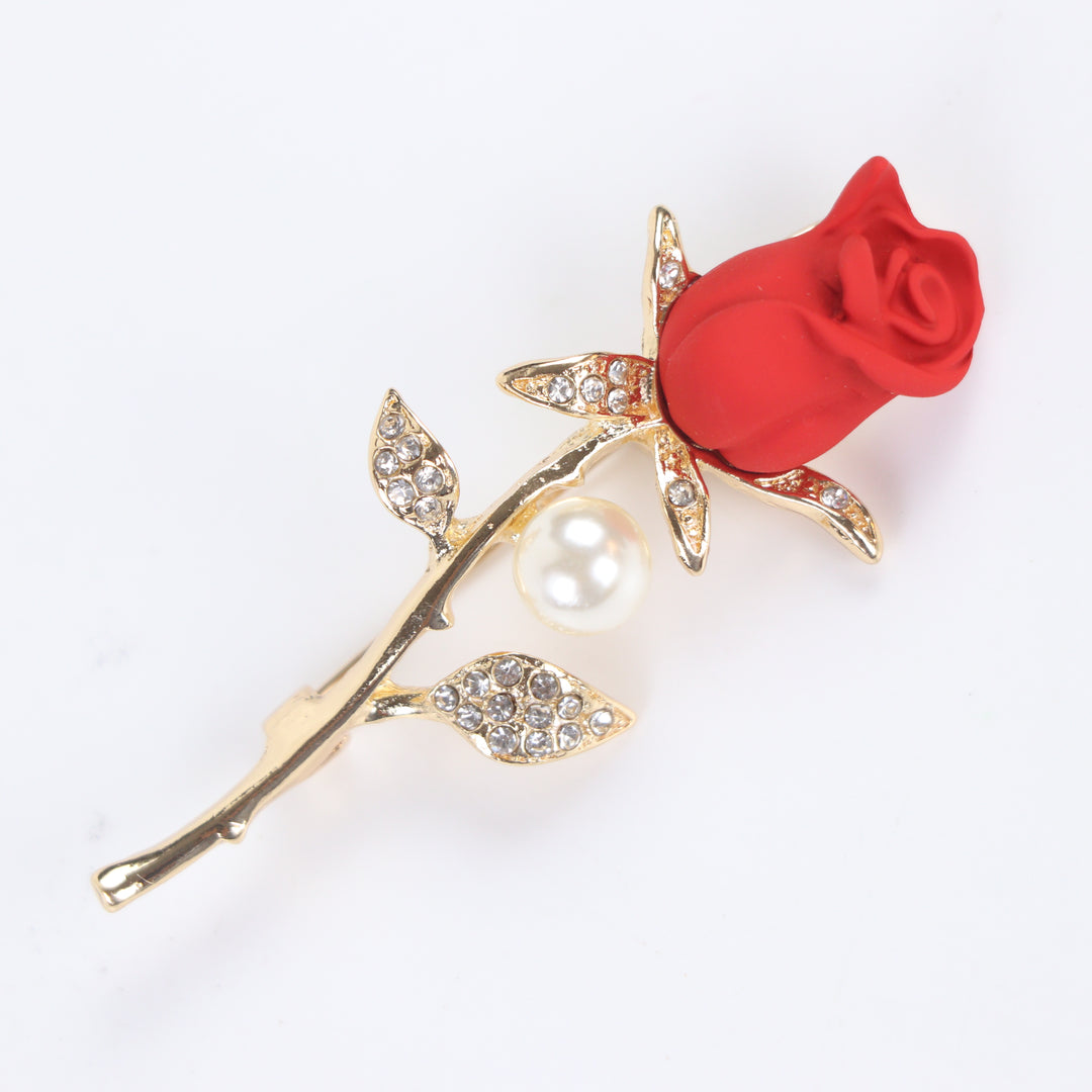 Matte red rose flower brooch pin with a pearl accent and pave crystal leaves on a gold stem against a white background by Delemon