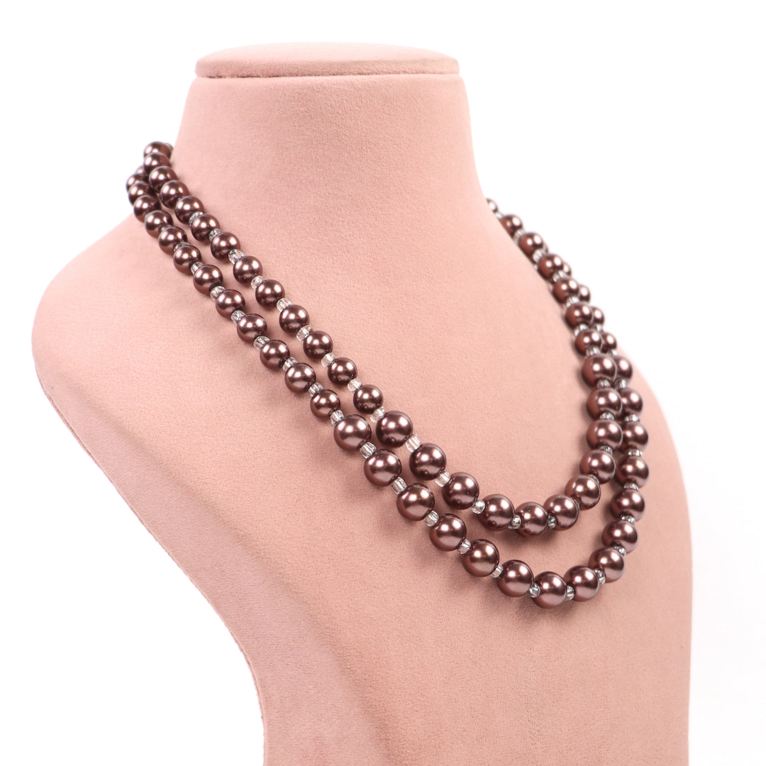 Text: Mocha metallic chocolate brown double-strand glass pearl necklace and matching earrings on a pink display - Delemon Collection.