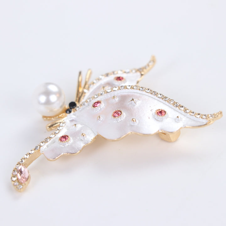 Pearlescent white enamel butterfly brooch pin with a large pearl accent and pink crystals against a white background by Delemon